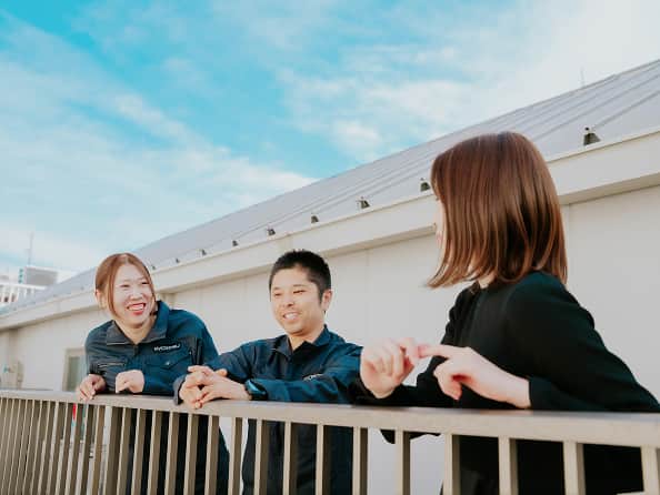 3人の社員が屋外で笑顔を見せる様子